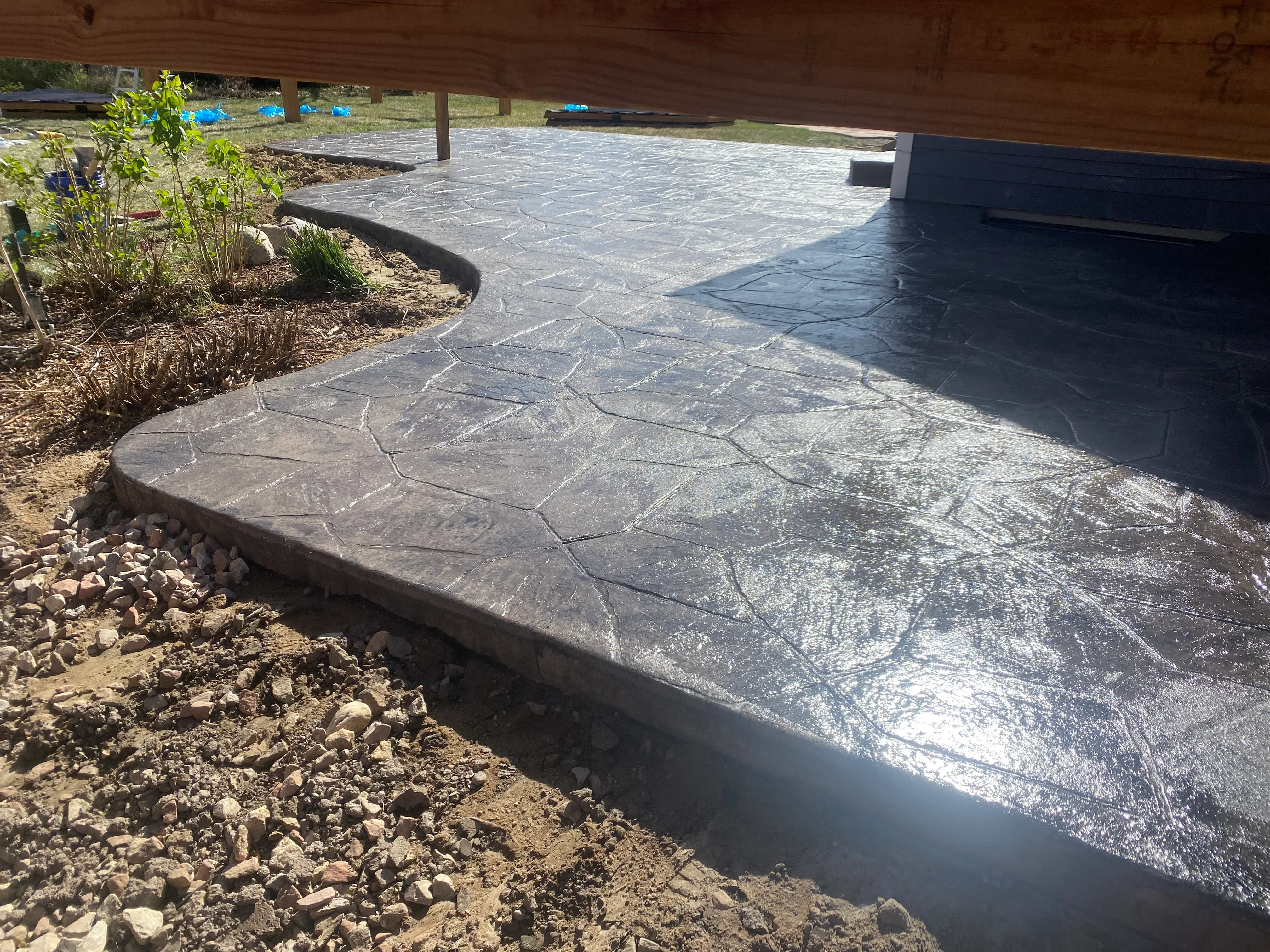 Stamped concrete patio with stone pattern, gravel border, and landscape bed integration